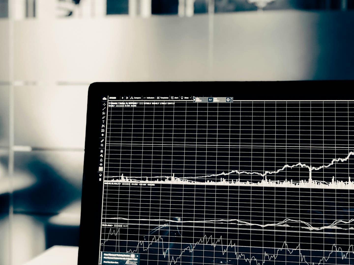 Schermo di un laptop con grafici finanziari su sfondo nero.